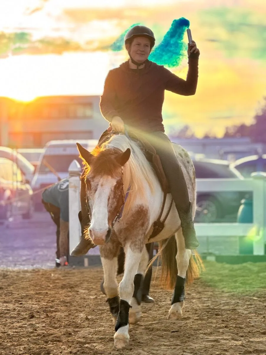 Pino galoppiert mit Kerstin und dem Einhorn im Abendlicht durch die Arena